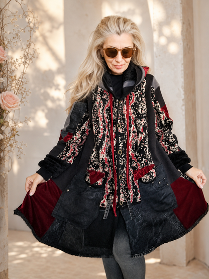 Woman modeling a handmade 3XL plus size black hooded patchwork cardigan with patterned knit fabric, dark denim panels, strawberry pink velvet pockets, furry cuffs and a flowing oversized silhouette by MARTINELI FASHION.